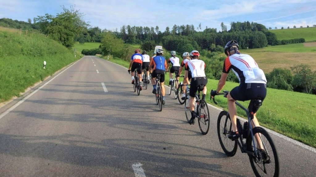Eine Gruppe Radfahrer mit Rennrädern fahren auf einer Straße.