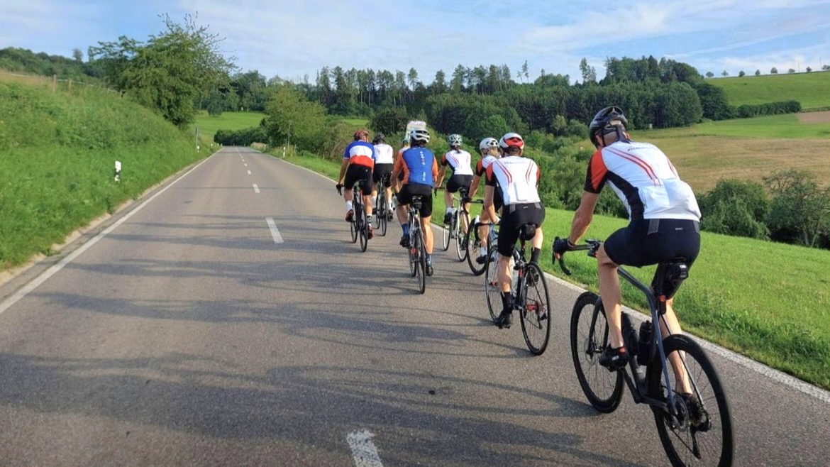 Eine Gruppe Radfahrer mit Rennrädern fahren auf einer Straße.